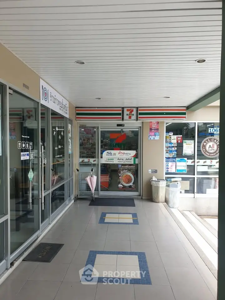 Convenience store entrance with glass doors and tiled flooring in a commercial building.