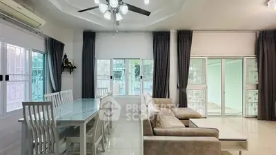 Spacious living room with modern dining area and cozy sofa, featuring large windows and elegant curtains.