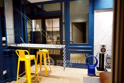 Stylish modern living room with vibrant yellow bar stools and sleek audio equipment.