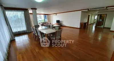 Spacious open-plan living and dining area with wooden flooring and modern furniture.