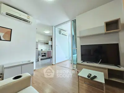 Modern living room with open kitchen and sleek furnishings in a bright apartment.