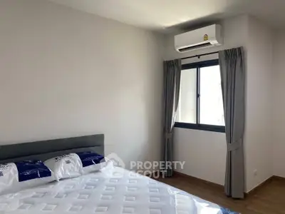 Modern bedroom with air conditioning and natural light, featuring a comfortable bed and stylish curtains.