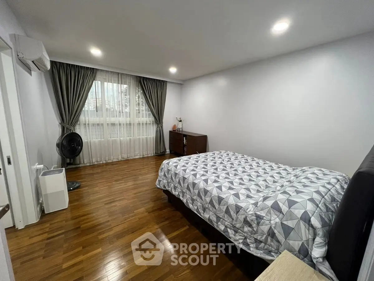 Spacious bedroom with wooden flooring and modern decor