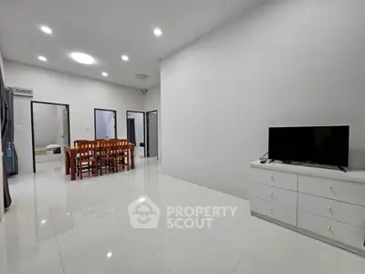 Spacious modern living room with sleek white tiles and elegant dining area.