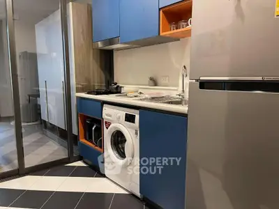 Modern kitchen with blue cabinets, washing machine, and sleek appliances.