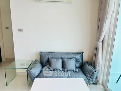 Modern living room with sleek sofa and glass side table, featuring minimalist decor and natural light.