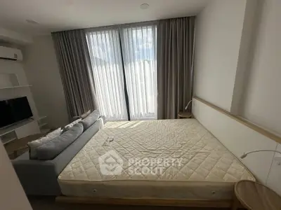 Spacious bedroom with large windows and modern furnishings in a stylish apartment.