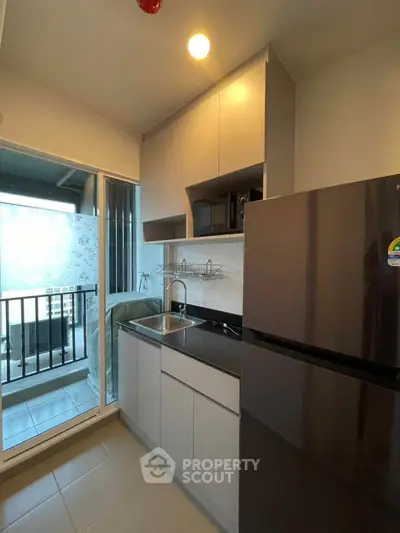 Modern kitchen with sleek cabinetry and balcony access in a stylish apartment.