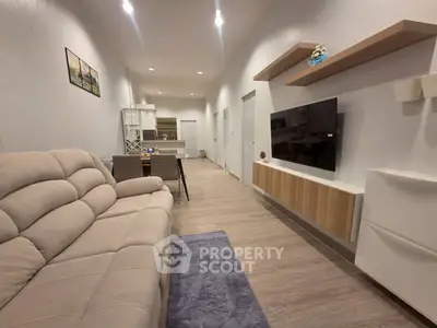 Modern living room with sleek design and open layout, featuring a comfortable sofa and wall-mounted TV.