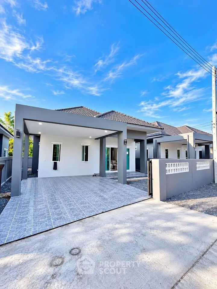 Modern single-story house with spacious driveway and sleek design under a clear blue sky.