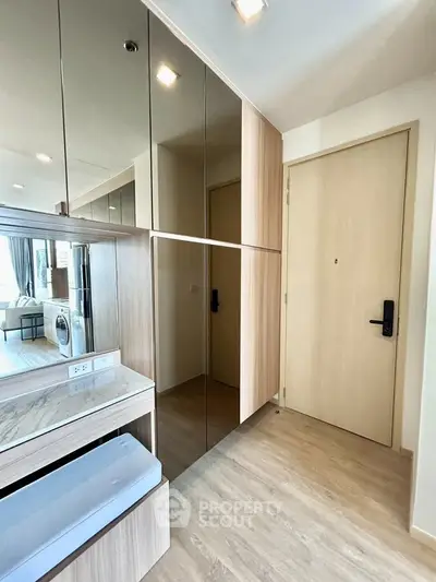 Modern apartment entrance with mirrored storage and sleek wooden flooring