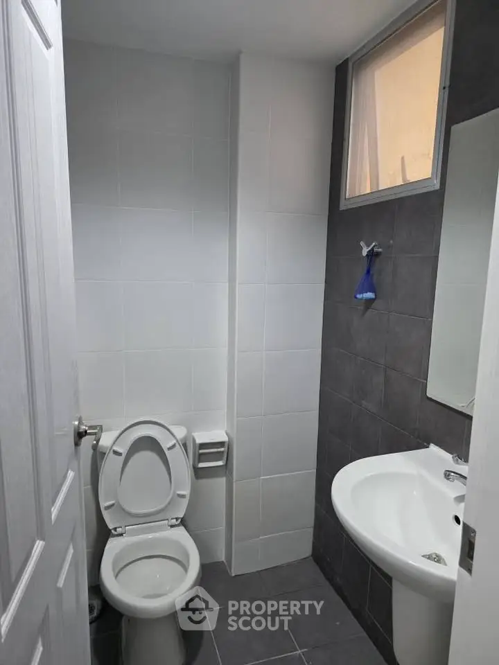 Modern bathroom with sleek white fixtures and dark tile accents