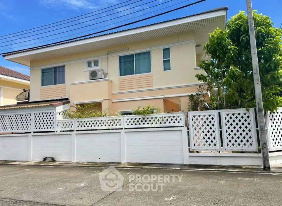 Charming two-story house with a white fence and lush greenery, perfect for family living.