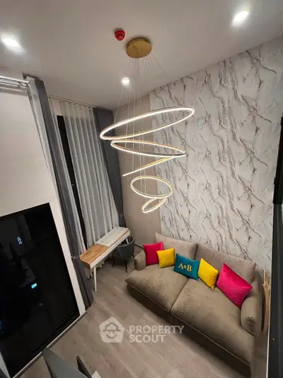 Modern living room with stylish lighting and cozy sofa, featuring vibrant accent pillows and elegant decor.