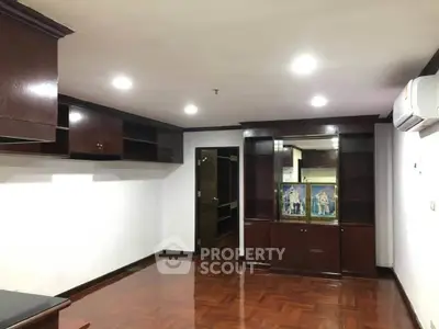 Spacious living room with wooden flooring and built-in cabinets, perfect for modern living.