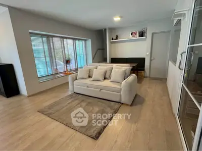 Spacious modern living room with large window and cozy seating area.