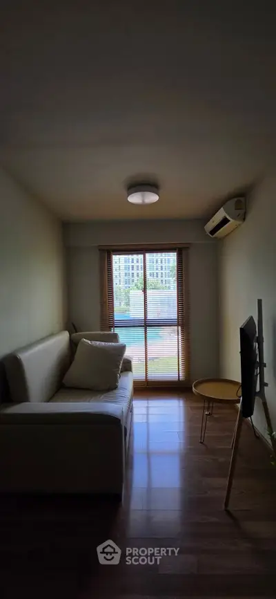 Cozy living room with modern sofa and large window offering natural light and city view.
