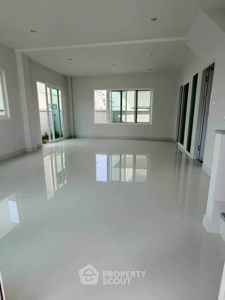Spacious modern living room with large windows and glossy tiled floors