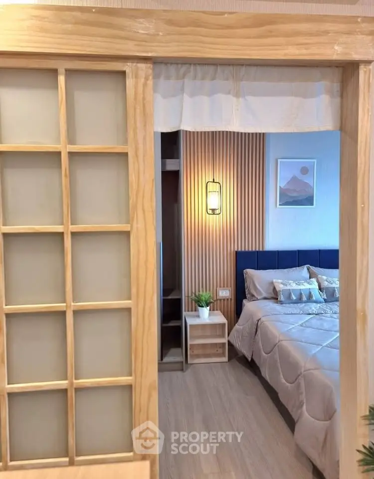 Cozy bedroom with modern decor and sliding wooden door, perfect for relaxation.