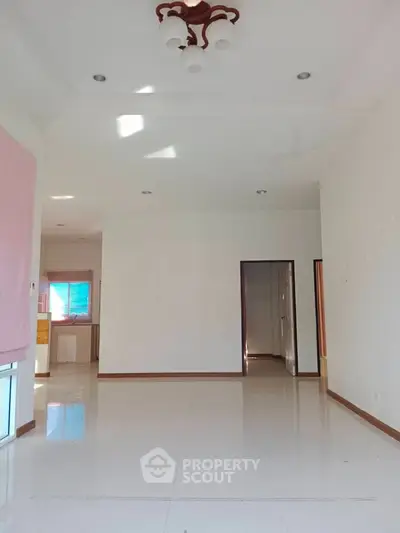 Spacious empty living room with white tiles and modern lighting