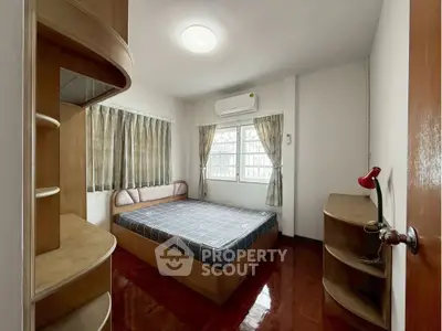 Cozy bedroom with wooden furniture and natural light, perfect for relaxation.