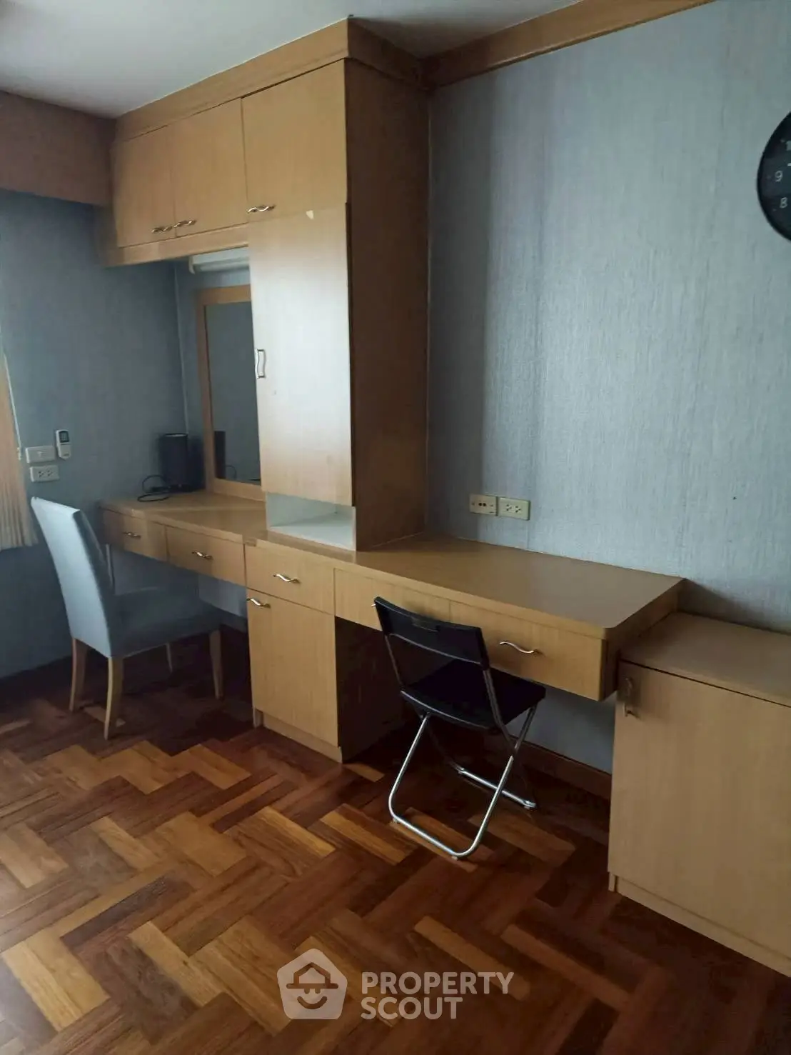 Spacious study room with built-in wooden desk and parquet flooring