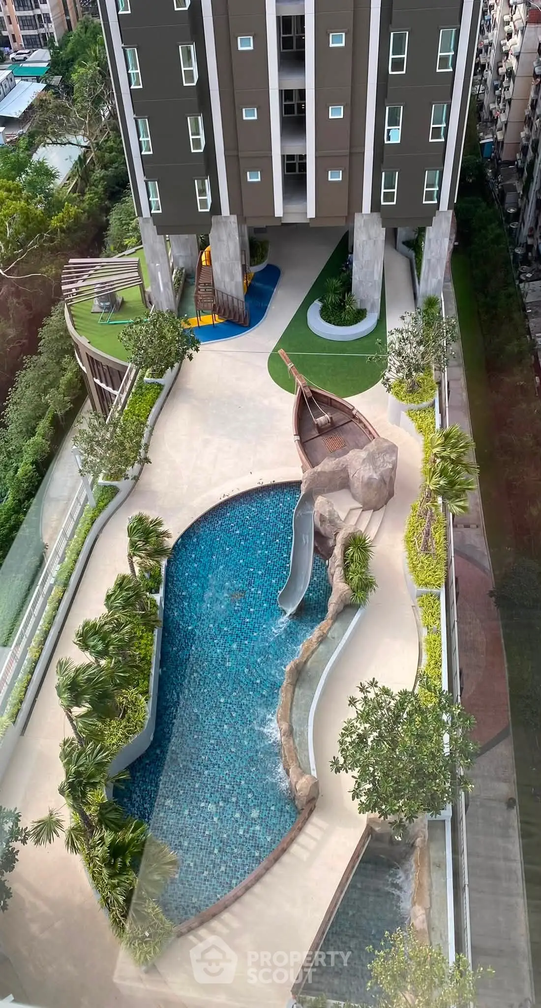 Stunning aerial view of modern apartment building with unique pool and lush landscaping.