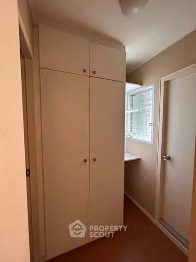Compact storage area with built-in cabinets and a small window, ideal for efficient space utilization.