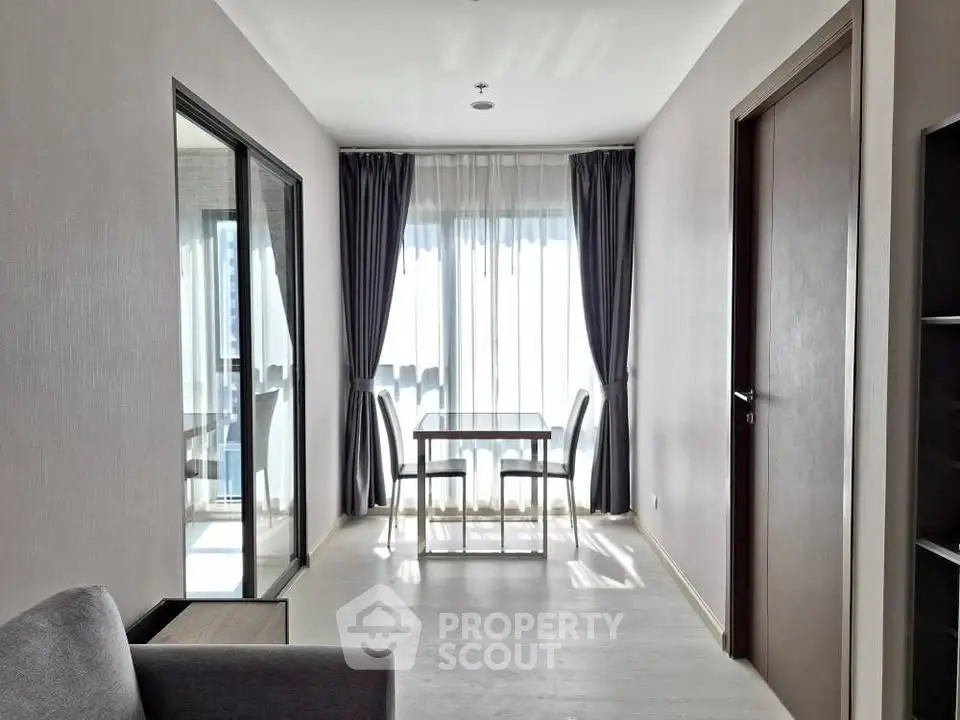 Bright dining area with modern glass table and chairs, featuring floor-to-ceiling windows and elegant curtains.