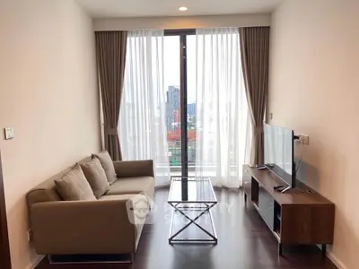 Modern living room with city view, featuring sleek furniture and floor-to-ceiling windows.