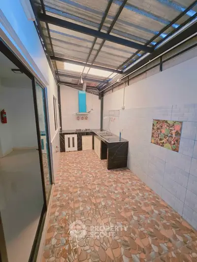 Charming semi-outdoor kitchen with unique stone flooring and modern appliances.