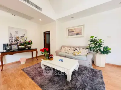 Charming living room with cozy sofa, elegant decor, and lush plants on wooden flooring.
