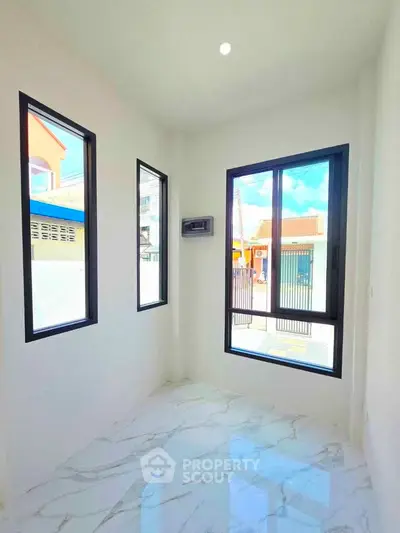 Bright room with large windows and marble flooring, perfect for a modern home office or study.