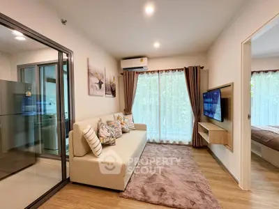 Modern living room with cozy sofa and wall-mounted TV, adjacent to a stylish kitchen.