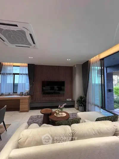 Luxurious living room with modern decor and large windows offering natural light and garden view.