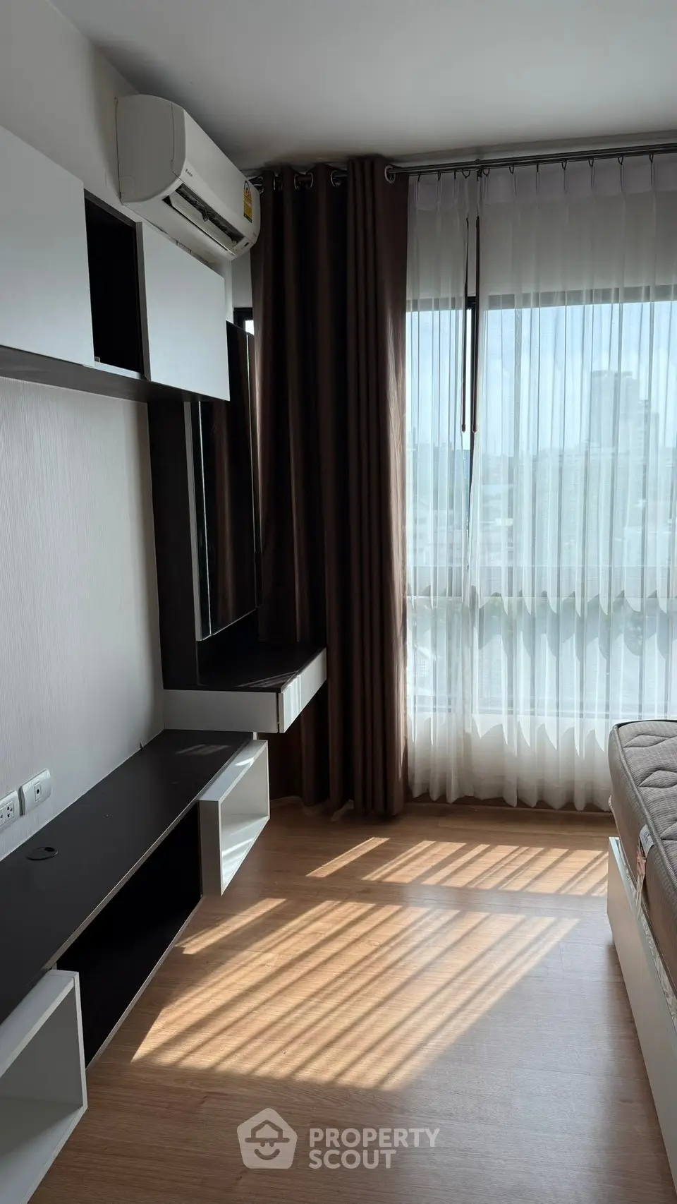 Modern bedroom with natural light, featuring sleek furniture and air conditioning, perfect for urban living.