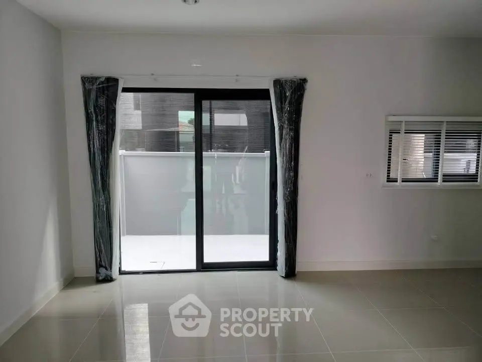 Spacious modern living room with large sliding glass doors and tiled flooring