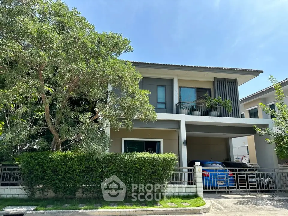 Modern two-story house with lush greenery and spacious driveway in a serene neighborhood.