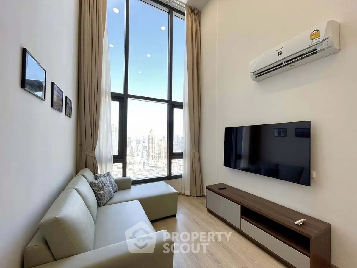 Modern living room with high ceilings and city view, featuring sleek furniture and large windows.