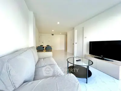 Spacious living room with modern sofa and flat-screen TV, perfect for relaxation.