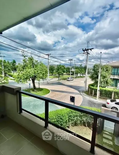 Spacious balcony with scenic view of lush greenery and residential street, perfect for relaxation.