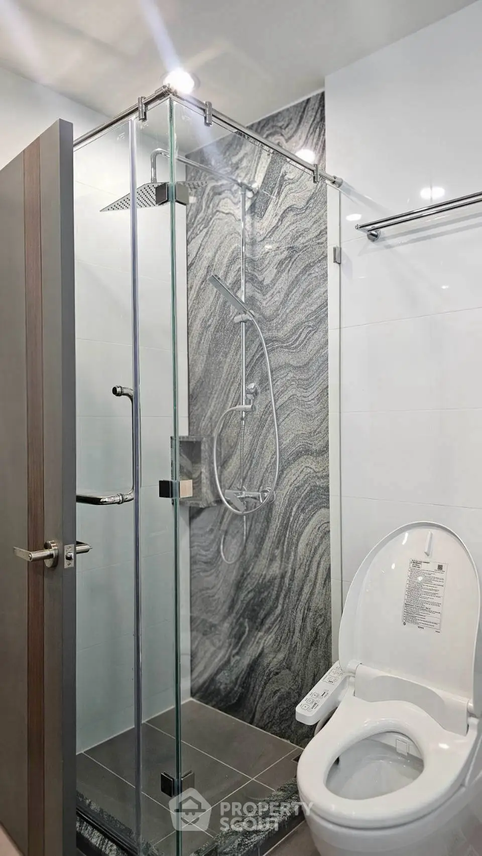 Modern bathroom with sleek glass shower and elegant marble wall design.
