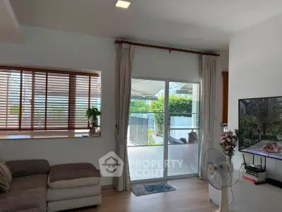 Charming living room with cozy sofa, large window, and balcony access, perfect for relaxation and entertaining.
