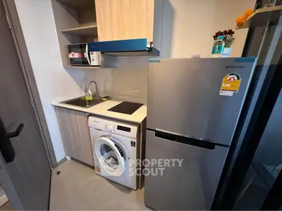 Compact modern kitchen with washing machine and fridge in a cozy apartment