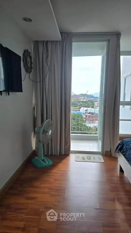 Bright bedroom with balcony view and wooden flooring