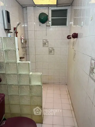 Cozy bathroom with unique glass block partition and floral tile accents.