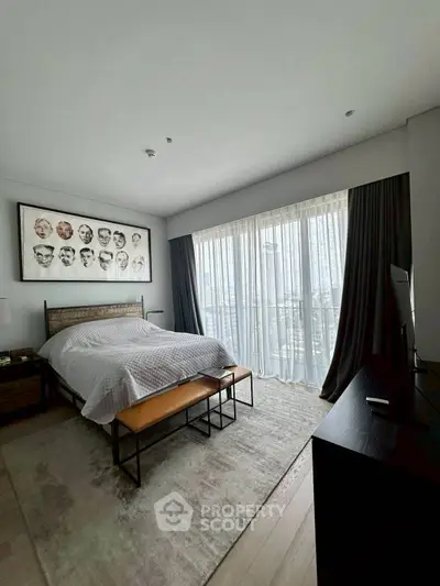 Spacious bedroom with modern decor and large window offering natural light