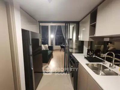 Modern open-layout kitchen with sleek appliances leading to a cozy living room with city view.