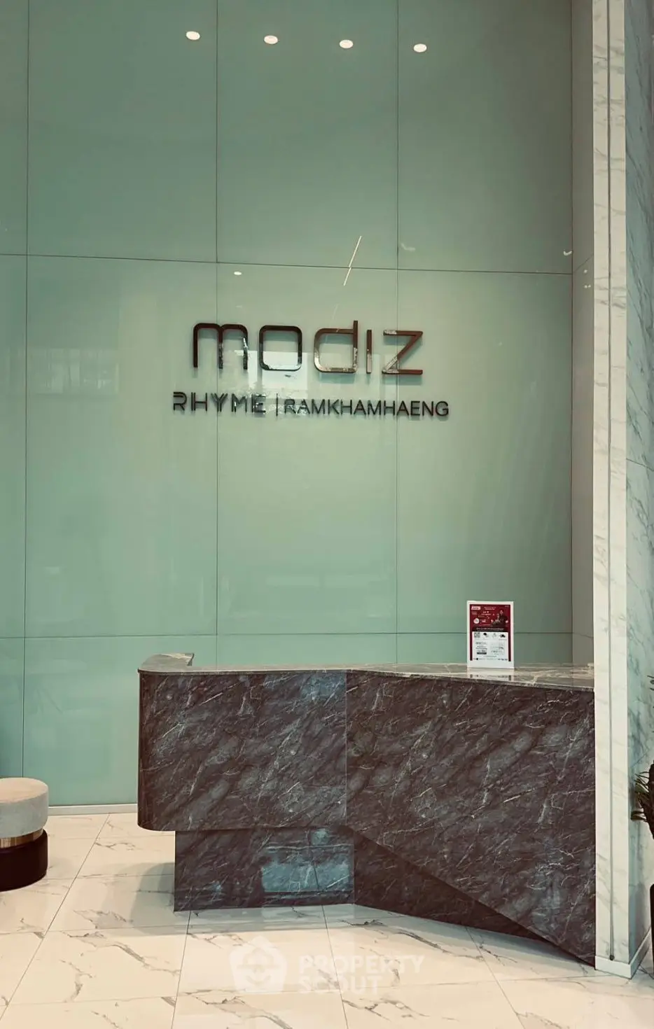 Elegant modern building entrance with sleek marble reception desk and stylish decor.
