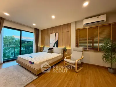 Spacious bedroom with modern decor and balcony view, featuring wooden flooring and stylish furniture.
